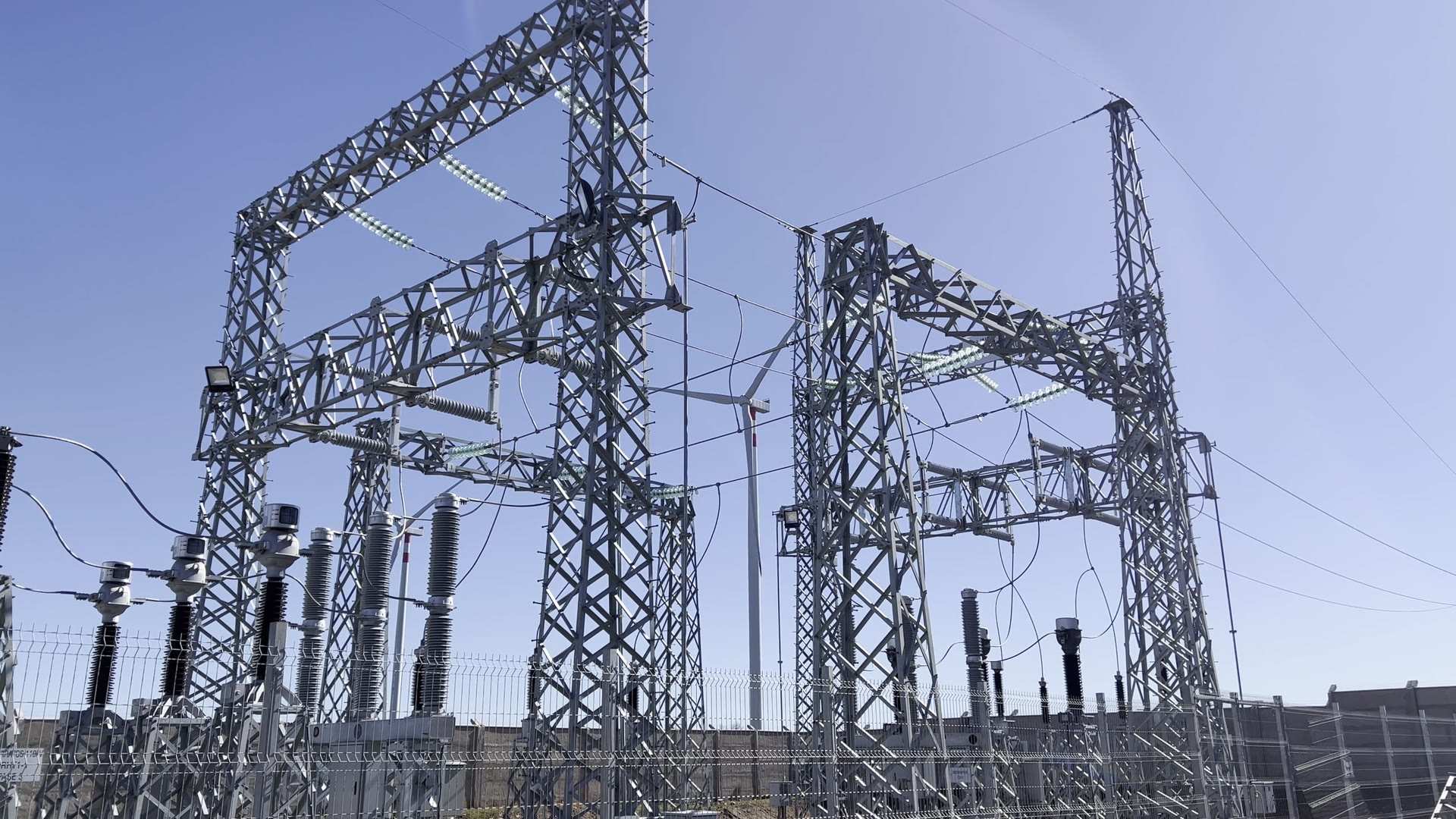 Circuit breakers, bushings and a steel gantry in a high-voltage substation against a clear sky